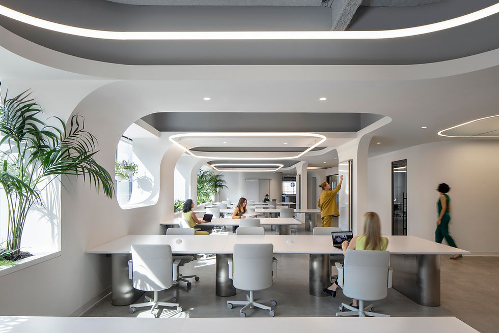 Bright and modern office workspace with long desks, ergonomic chairs, and ample natural light. Office design by Henricksen.