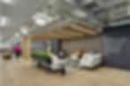Contemporary office waiting area with modern sofas, armchairs, and a unique green wall feature. Office furniture solutions by Henricksen.
