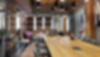 Modern conference room with long table, chairs, and stylish lighting.