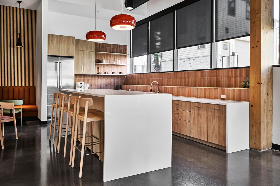 Modern office kitchen or break room with a large island, bar seating, and open shelving. Office design by Henricksen.