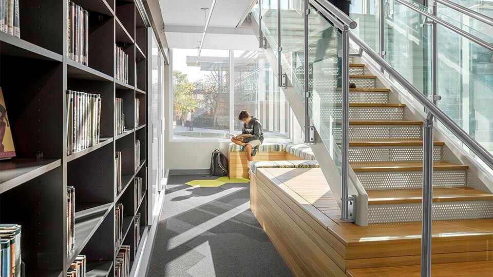 Modern office interior with exposed ductwork, glass-walled offices, and contemporary workstations.